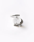 A rhodium‑color plated ring featuring clear glass fragments inspired by melting glaciers, held between two metal bands.