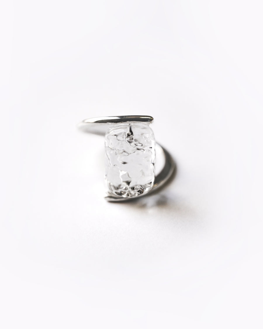 A rhodium‑color plated ring featuring clear glass fragments inspired by melting glaciers, held between two metal bands.