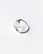 A rhodium‑color plated ring featuring clear glass fragments inspired by melting glaciers, held between two metal bands.