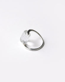 A rhodium‑color plated ring featuring clear glass fragments inspired by melting glaciers, held between two metal bands.