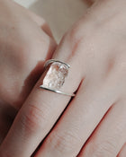 Clear, glacier‑like glass pieces secured between two rhodium‑plated bands in a ring design that curves softly around the finger.