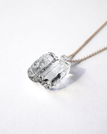 “Clear, glacier‑like glass pieces that catch the light, suspended from an adjustable gold‑plated chain.