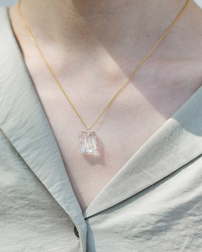 n adjustable gold‑plated necklace featuring clear glass forms inspired by melting glaciers.