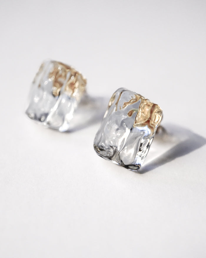 Gold‑plated stud earrings with transparent, glacier‑like glass pieces that shimmer with fresh, glossy clarity.