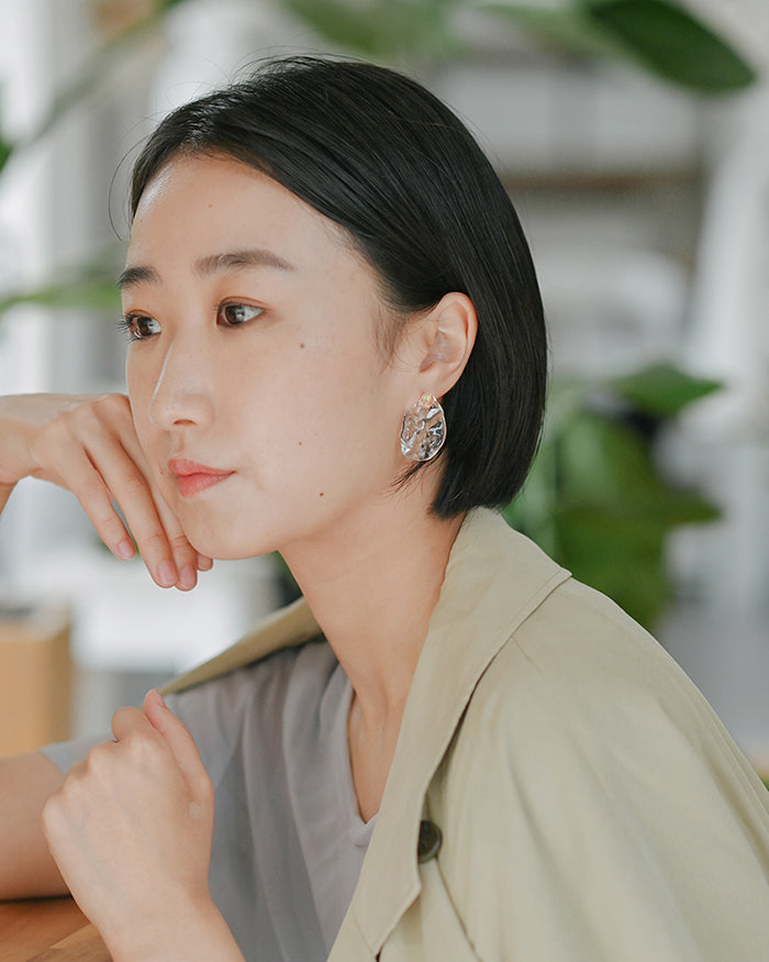 Gold‑plated stud earrings with clear glass shaped like gentle waves of light, shimmering softly like reflections on a lake.