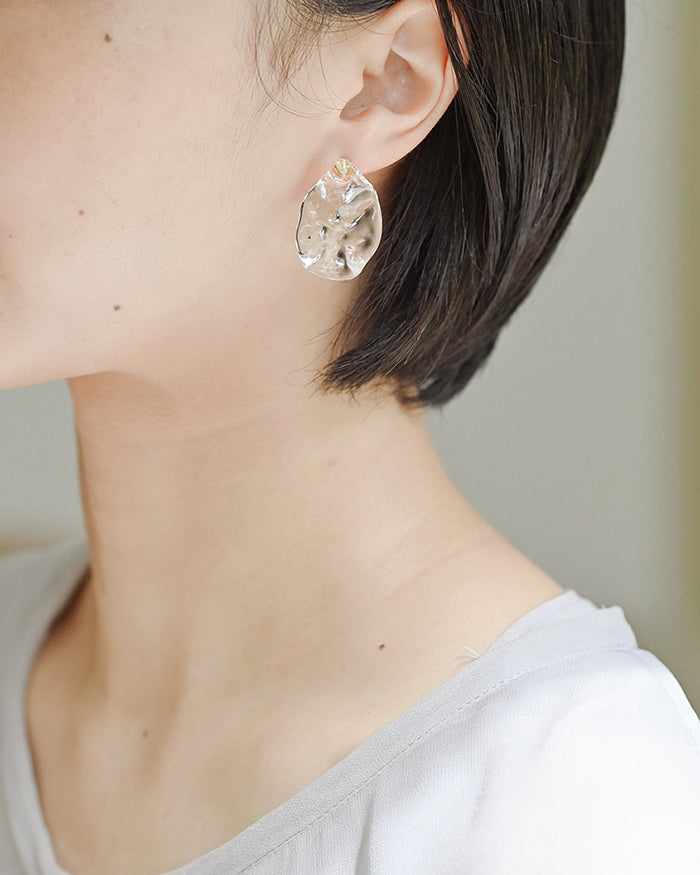 Gold‑plated stud earrings with clear glass shaped like gentle waves of light, shimmering softly like reflections on a lake.