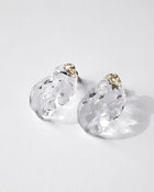 Gold‑plated stud earrings with clear glass shaped like gentle waves of light, shimmering softly like reflections on a lake.