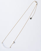 A gold‑plated necklace with a gentle arch and a textured glass motif, accented with a single freshwater pearl and featuring an adjustable chain length.