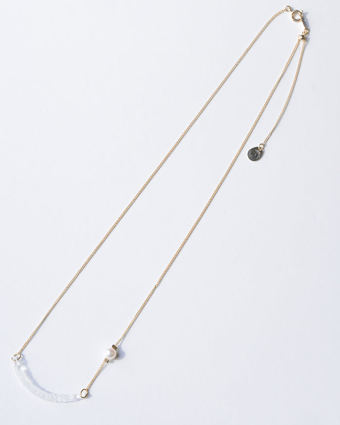 A gold‑plated necklace with a gentle arch and a textured glass motif, accented with a single freshwater pearl and featuring an adjustable chain length.