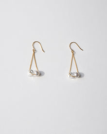 Gold‑plated drop earrings featuring a single freshwater pearl and a small hollow glass sphere suspended from a delicate chain.