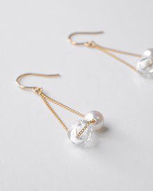Gold‑plated drop earrings featuring a single freshwater pearl and a small hollow glass sphere suspended from a delicate chain.