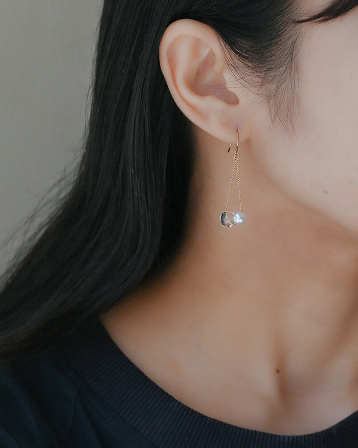 Gold‑plated drop earrings featuring a single freshwater pearl and a small hollow glass sphere suspended from a delicate chain.