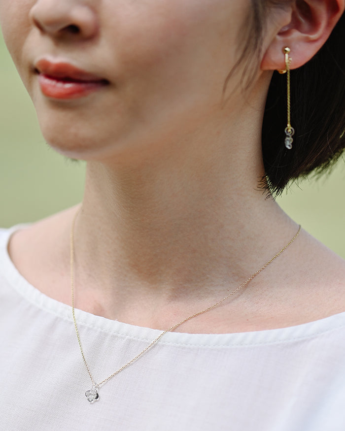 A small hydrangea-shaped glass pendant in soft gray, attached to a brass chain with nickel-free gold plating and an adjustable slide ball.