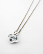 A small hydrangea-shaped glass pendant in soft gray, attached to a brass chain with nickel-free gold plating and an adjustable slide ball.