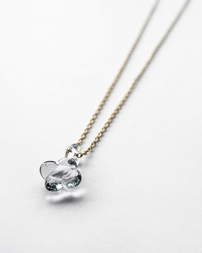 A small hydrangea-shaped glass pendant in soft gray, attached to a brass chain with nickel-free gold plating and an adjustable slide ball.