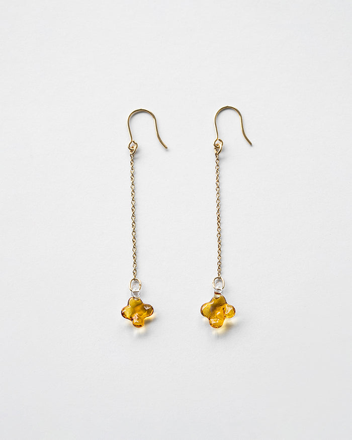A pair of earrings featuring tiny osmanthus-inspired glass blossoms in glossy amber tones. The delicate flowers hang from gold‑plated hooks by fine chains, gently swaying and evoking the soft shimmer and sweet fragrance of osmanthus.