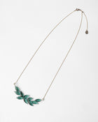 A necklace featuring a gentle arch of fresh green leaves, crafted in glass and suspended from a delicate gold‑plated chain. The design captures the vitality of new spring foliage, as if light has been softly lifted from overlapping leaves and transformed into an accessory.