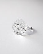 “A handmade transparent glass ring accented with a single, intricately formed glass flower.