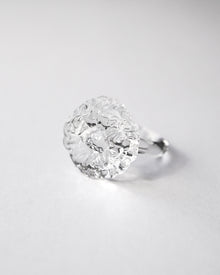 “A handmade transparent glass ring accented with a single, intricately formed glass flower.
