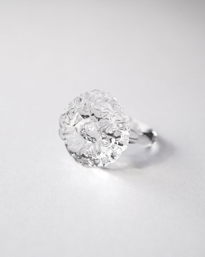“A handmade transparent glass ring accented with a single, intricately formed glass flower.