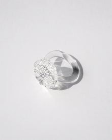 “A handmade transparent glass ring accented with a single, intricately formed glass flower.