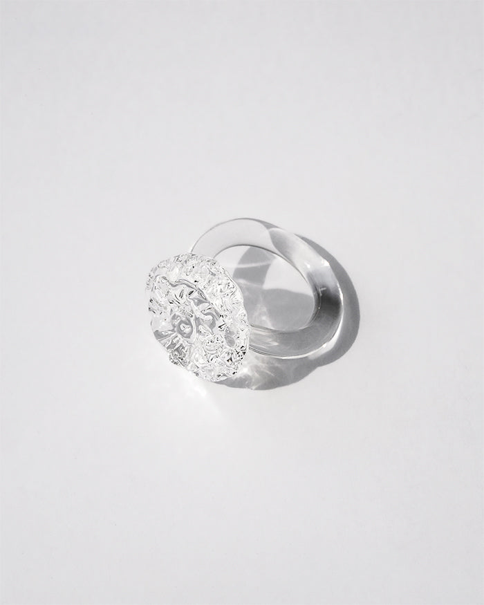 “A handmade transparent glass ring accented with a single, intricately formed glass flower.