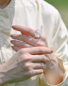 A delicate glass artwork inspired by flowers opening toward the sun, featuring finely shaped translucent petals that reflect light with soft brilliance. A handmade glass ring, carefully shaped by artisans, showcasing clear and luminous glasswork.