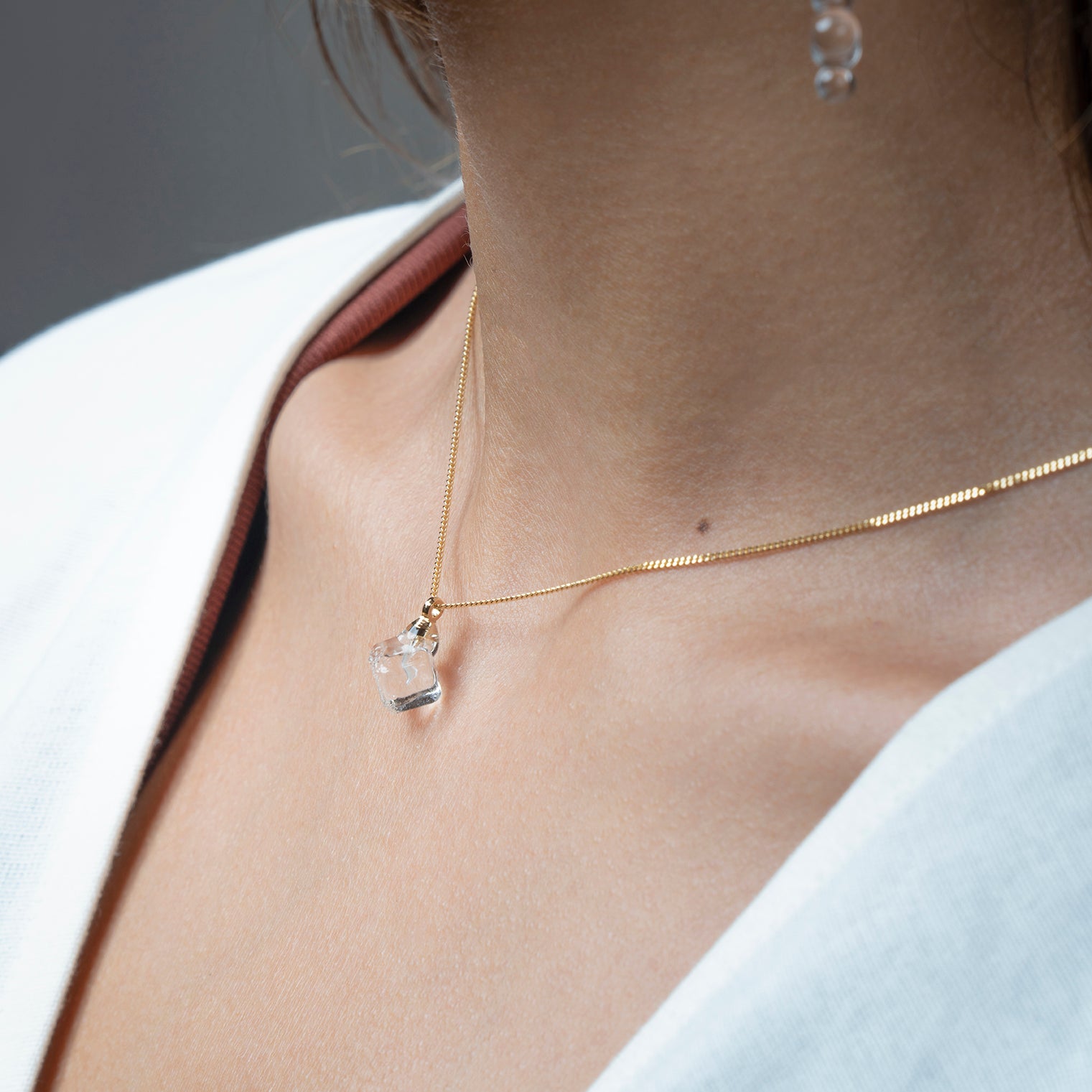 “A soft cube-shaped handmade glass pendant combining textured frosted and smooth surfaces, attached to a 500mm gold necklace chain with an adjustable ball clasp.