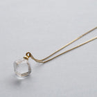 “A soft cube-shaped handmade glass pendant combining textured frosted sides and smooth surfaces, attached to a slender gold chain.