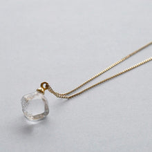 “A soft cube-shaped handmade glass pendant combining textured frosted sides and smooth surfaces, attached to a slender gold chain.