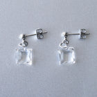 Delicate stud earrings with moonlight‑like soft glass cubes, finished in rhodium‑color plating.