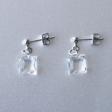 Delicate stud earrings with moonlight‑like soft glass cubes, finished in rhodium‑color plating.