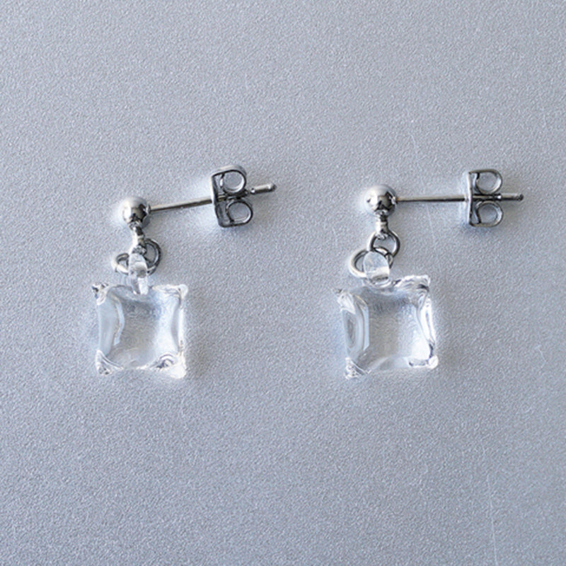 Delicate stud earrings with moonlight‑like soft glass cubes, finished in rhodium‑color plating.