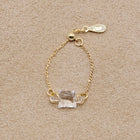 “A gold-plated adjustable ring featuring a soft cube-shaped glass element with contrasting frosted and smooth surfaces that evoke moonlight.