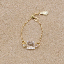 “A gold-plated adjustable ring featuring a soft cube-shaped glass element with contrasting frosted and smooth surfaces that evoke moonlight.