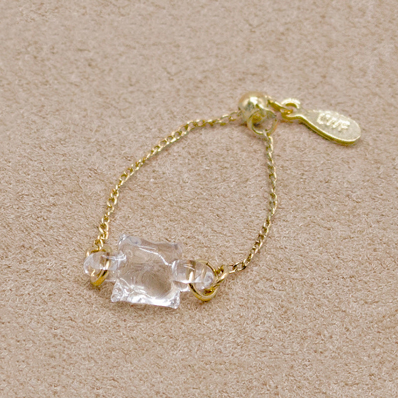 “A gold-plated adjustable ring featuring a soft cube-shaped glass element with contrasting frosted and smooth surfaces that evoke moonlight.