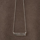 A frosted, sherbet-textured handmade glass pendant hanging from a delicate necklace chain.