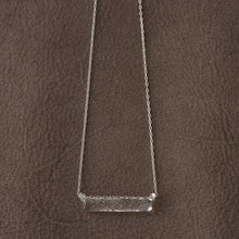 A frosted, sherbet-textured handmade glass pendant hanging from a delicate necklace chain.
