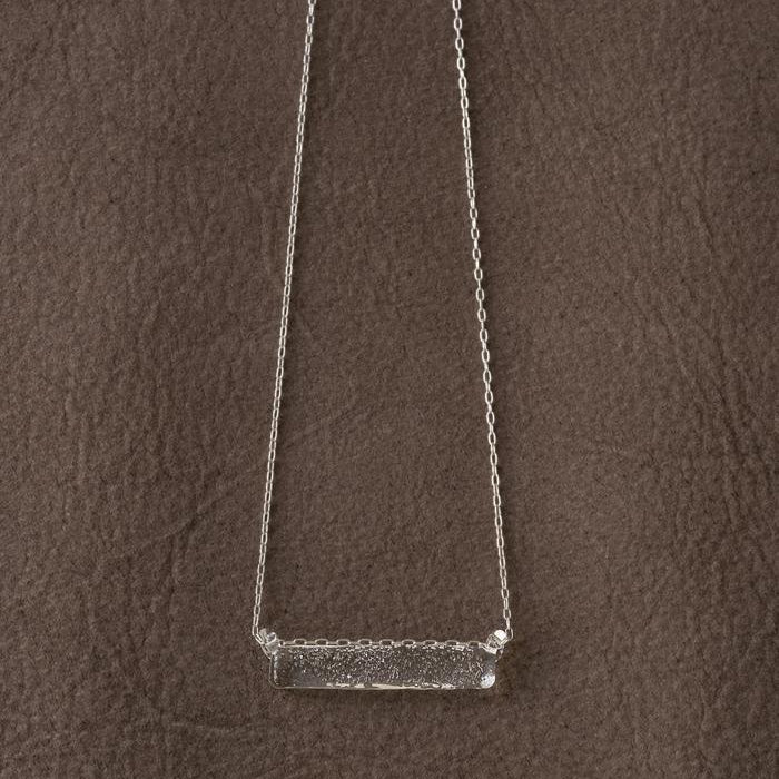 A frosted, sherbet-textured handmade glass pendant hanging from a delicate necklace chain.