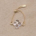 A small four‑petal handmade glass flower set on an adjustable gold‑plated chain ring.