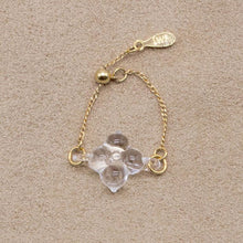 A small four‑petal handmade glass flower set on an adjustable gold‑plated chain ring.