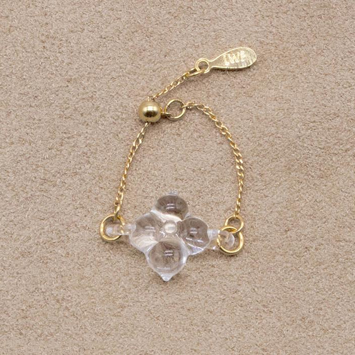 A small four‑petal handmade glass flower set on an adjustable gold‑plated chain ring.