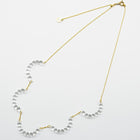 A necklace made of five connected arcs that resemble softly rounded water droplets, attached to a gold‑plated chain with an adjustable sliding ball.
