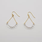 Handmade glass arc pieces resembling gathered water droplets, suspended at both ends by twin gold‑plated chains from a hook.