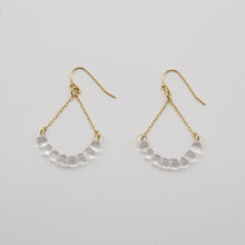 Handmade glass arc pieces resembling gathered water droplets, suspended at both ends by twin gold‑plated chains from a hook.